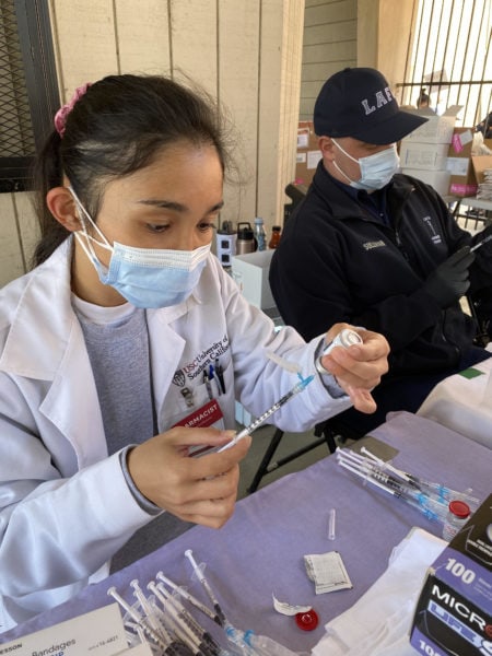 USC pharmacist fills a syringe for a vaccine